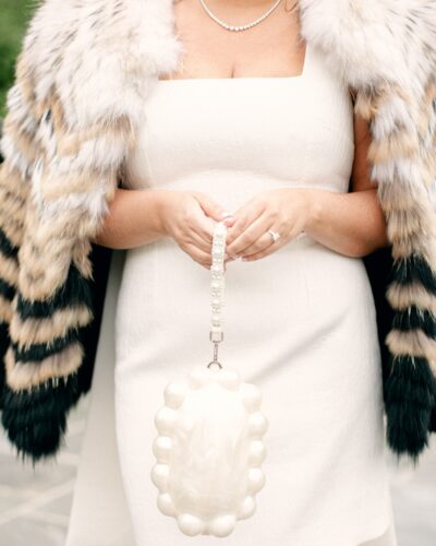 white dress with pearl bag and faux fur jacket