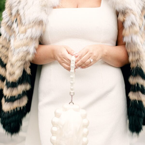 white dress with pearl bag and faux fur jacket