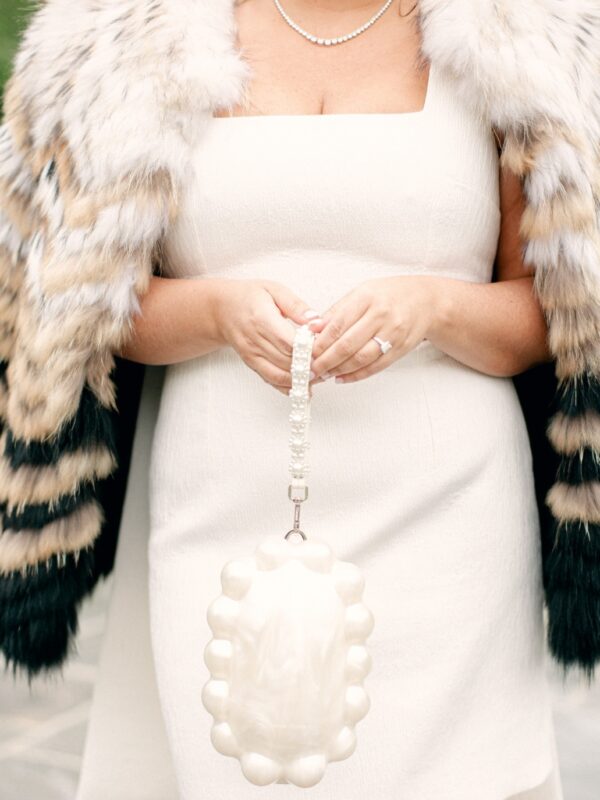 white dress with pearl bag and faux fur jacket